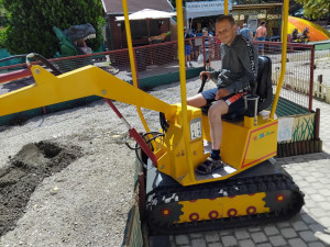 Lakónk mosolyogva pózol egy játék kotrógép fülkéjéből