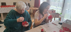 Ilona és Bernadett koncentrálva festik a PET-palack aljából kivágott műanyag virágokat